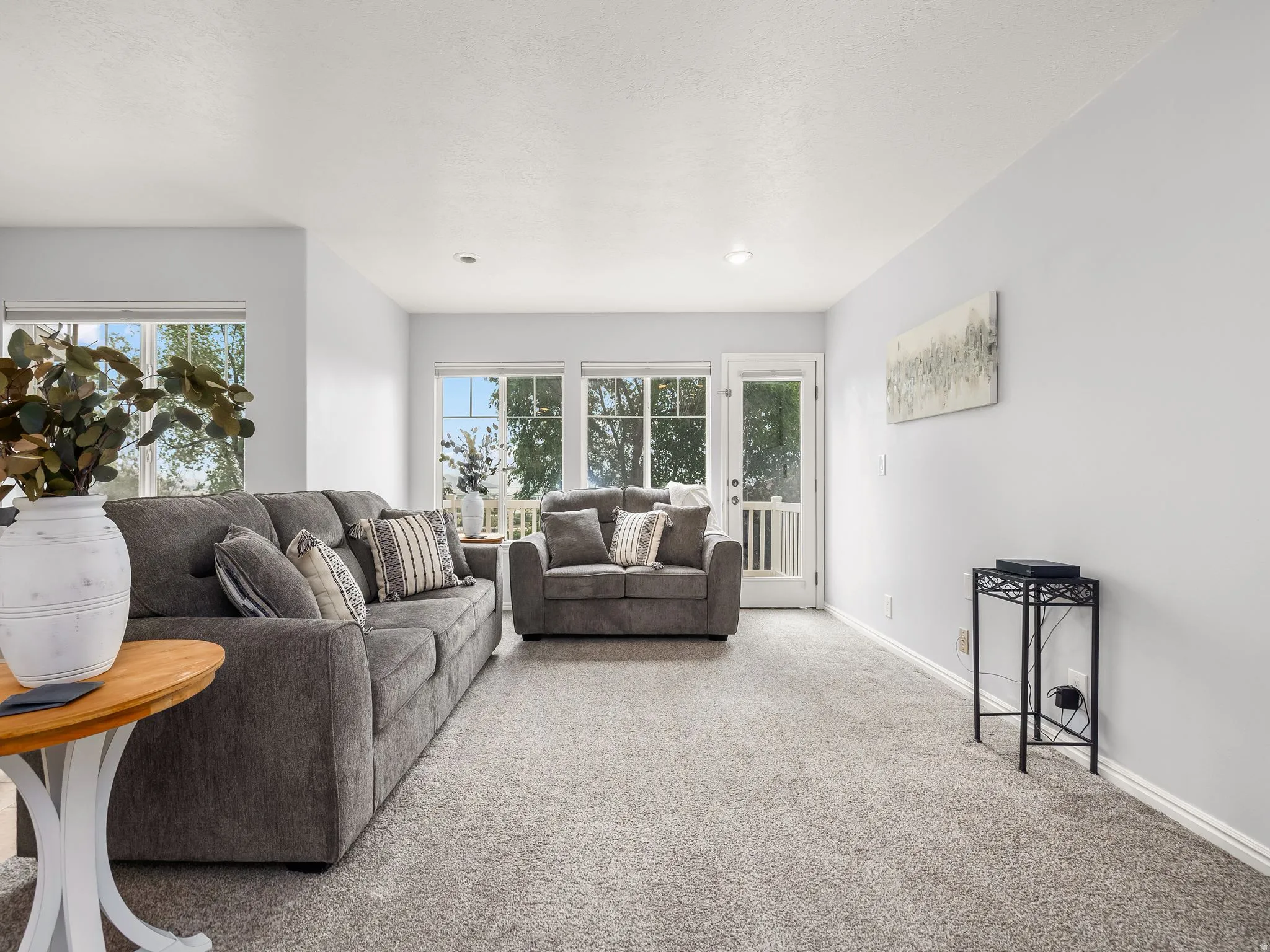Bright living area featuring light gray wall paint, light gray carpeting, recessed lighting, and white baseboards