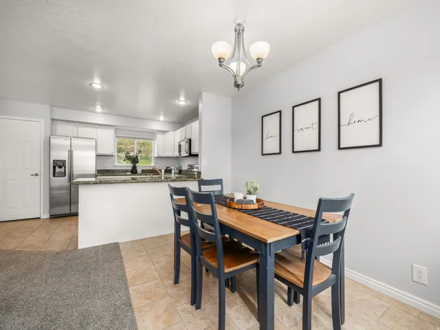 Open-concept kitchen and dining area featuring tile flooring, white cabinetry, stainless steel appliances, and recessed lighting