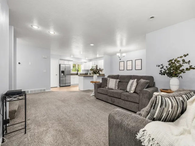 Open-concept living space featuring recessed lighting, light gray walls, and textured carpeting