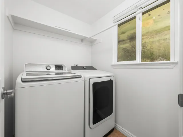 Dedicated laundry room featuring a large window, integrated shelving, and a hanging rod