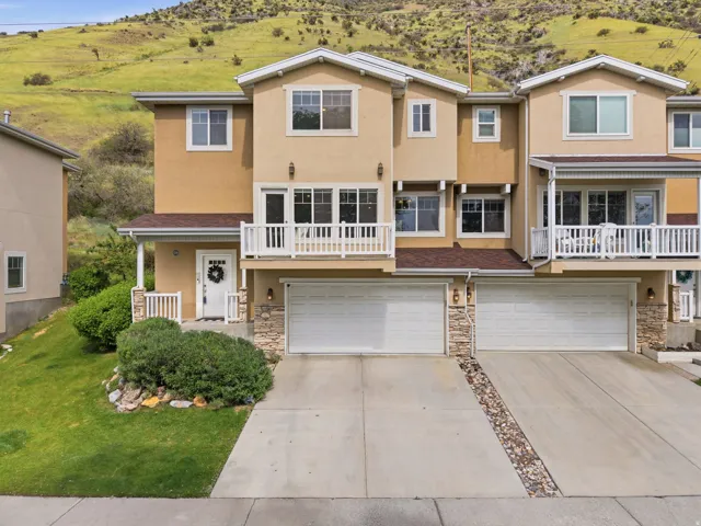 Stucco exterior with multiple balconies, two-car garage, and a covered front porch