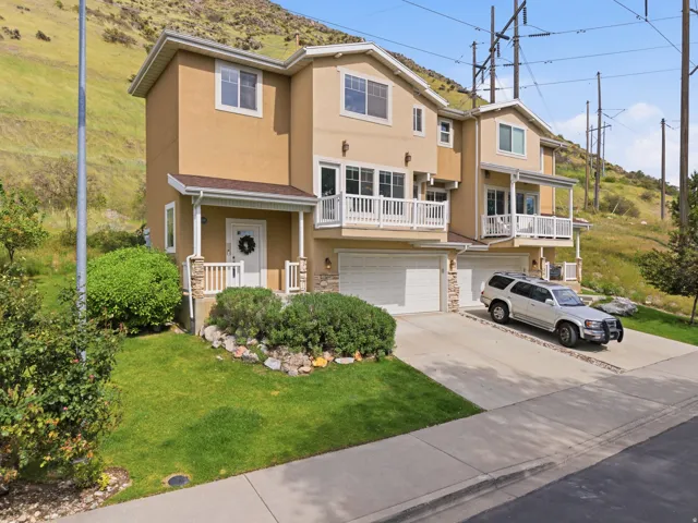 Stucco exterior with stone accents, featuring a two-car garage, covered entry, and upper-level balcony