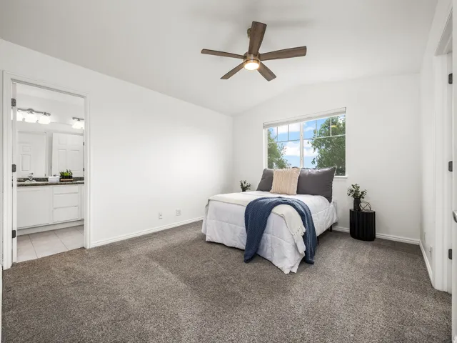Carpeted bedroom with a vaulted ceiling and ceiling fan