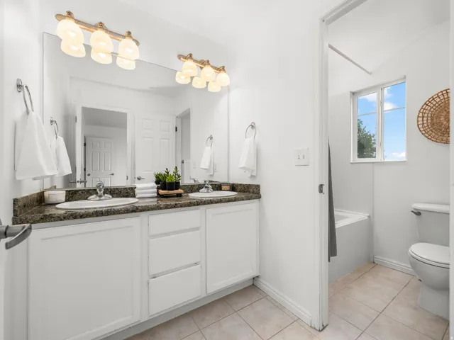 Dual vanity with white cabinetry, a dark speckled countertop, and under-mount sinks