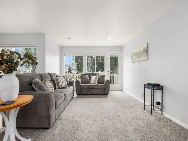 Bright living area featuring light gray wall paint, light gray carpeting, recessed lighting, and white baseboards