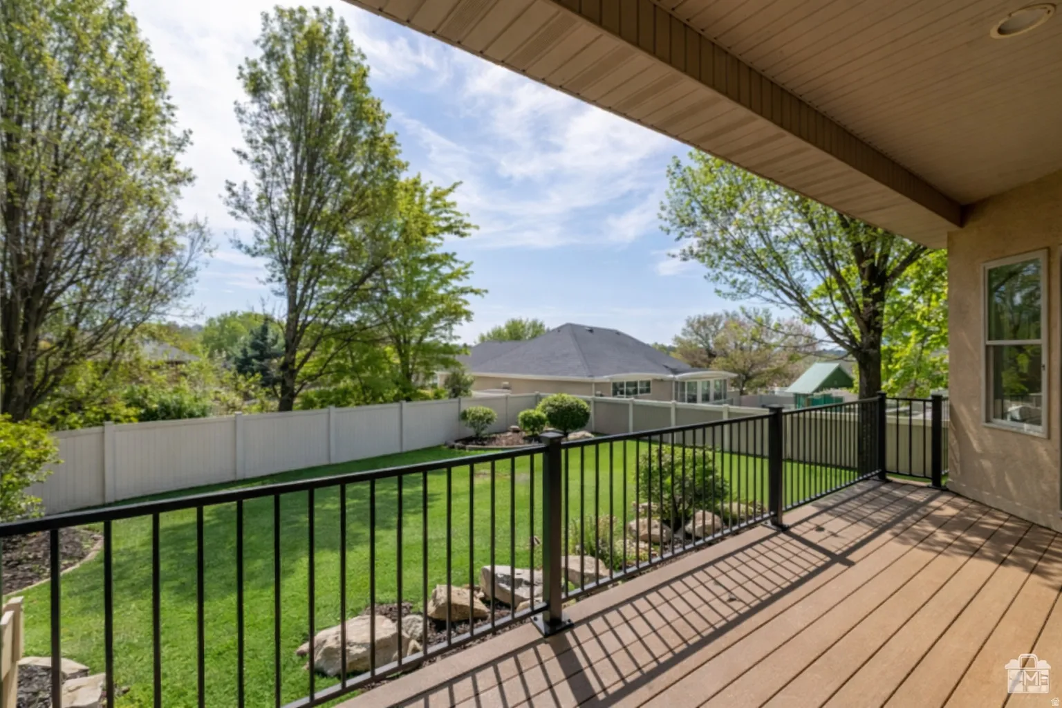 Spacious covered deck featuring wood-finish composite decking and black metal railings.
