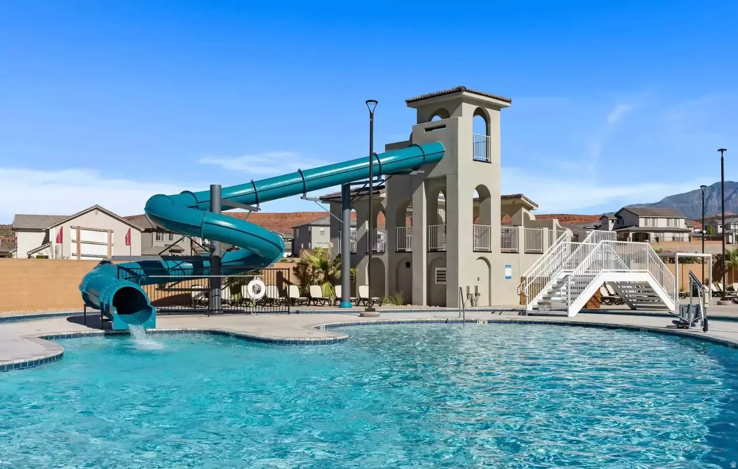 Community swimming pool featuring a curved water slide, multi-level structure with arched openings, and ample lounging space