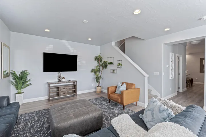 Bright living area featuring recessed lighting, light wood-finish flooring, and a staircase with white risers and handrail