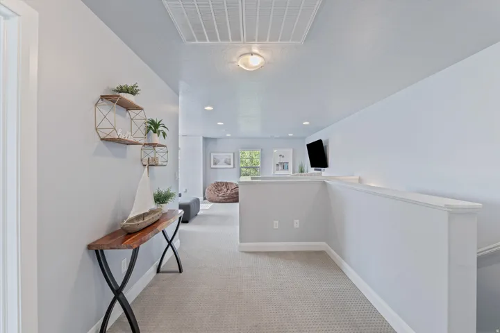 Carpeted hall with recessed lighting, a white painted half-wall, and an attic access panel