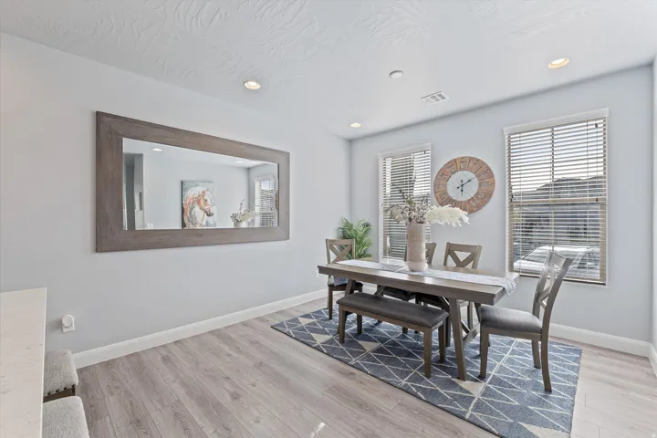 Dining area featuring wood-finish flooring, two large windows with blinds, recessed lighting, and a neutral color palette