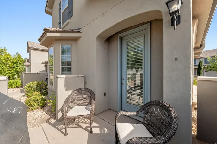 Private patio area featuring a light stucco exterior and a transom door with integrated blinds