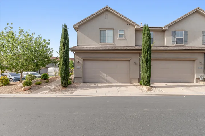 Stucco exterior with an attached garage, landscaped rock bed, and a concrete driveway