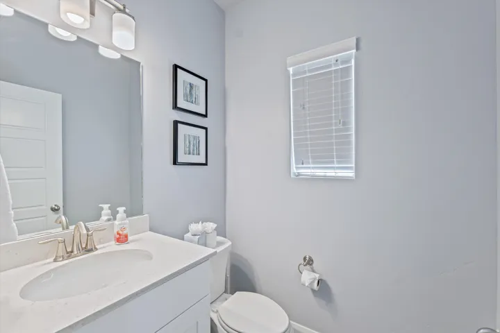 Bathroom featuring a white vanity with integrated sink, brushed nickel faucet, and coordinating light fixture