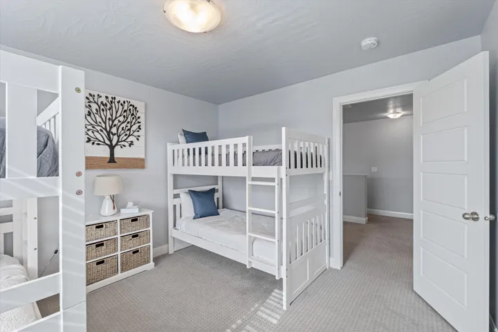 Carpeted room featuring bunk beds, a storage dresser with woven baskets, and a ceiling-mounted light fixture
