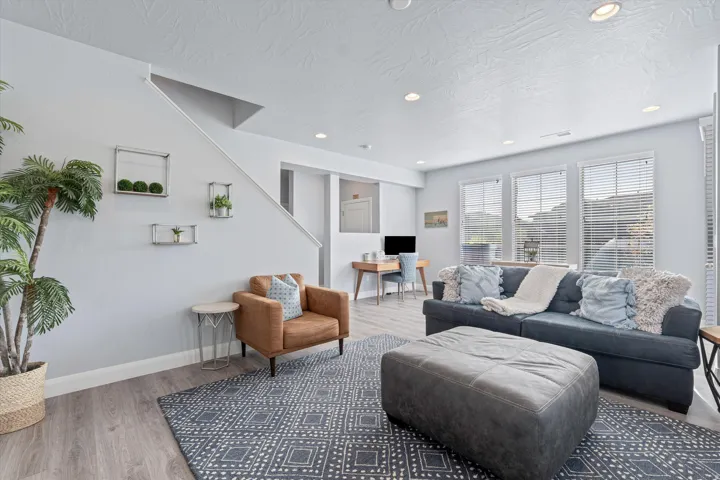 Open-concept living area featuring recessed lighting, wood-finish flooring, and multiple windows with blinds