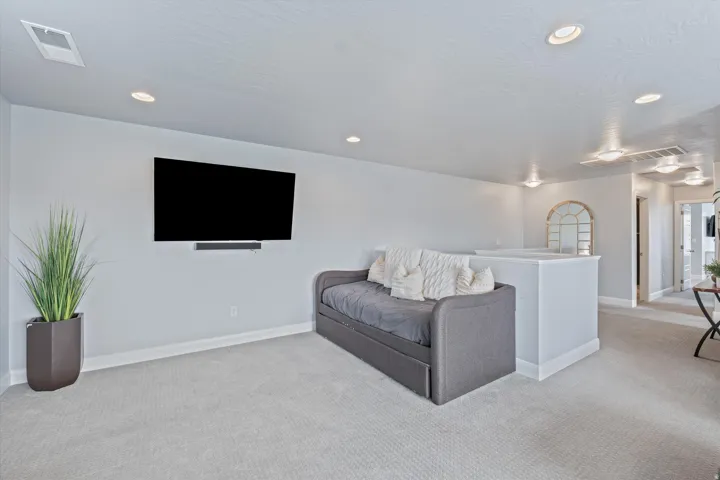 Carpeted open area featuring recessed lighting, a built-in entertainment wall, and a half-wall partition