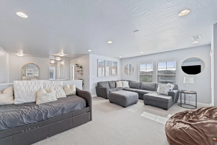 Spacious carpeted room featuring recessed lighting and multiple windows with horizontal blinds