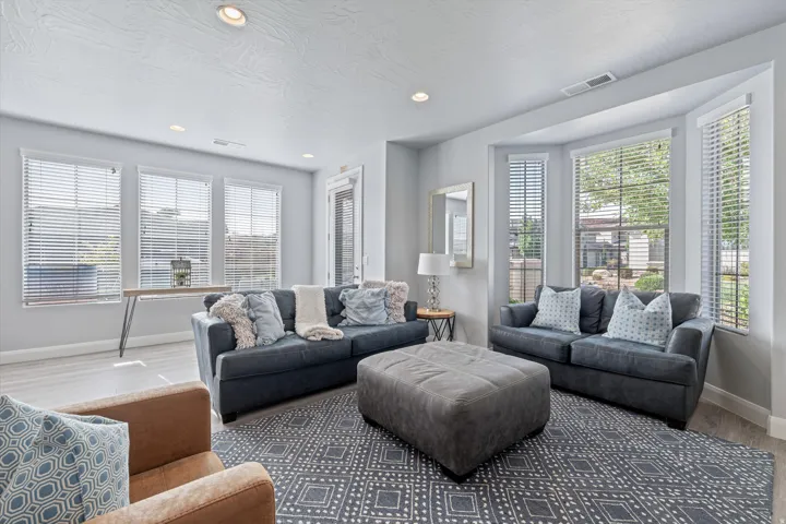 Spacious living area featuring light-toned wood-finish flooring and a geometric pattern area rug