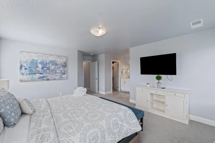 Bedroom featuring light blue walls, gray carpet flooring, a ceiling-mounted light fixture, and a built-in white media console