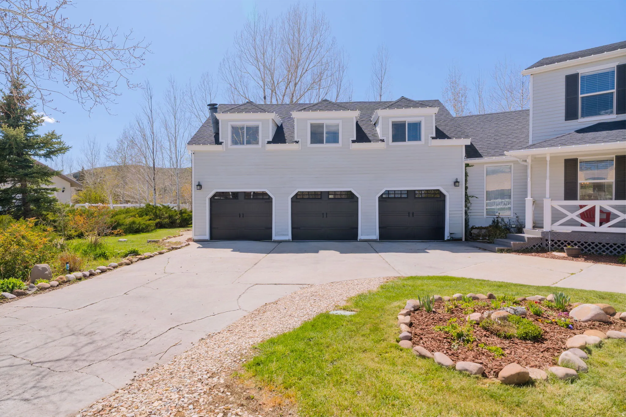 Light-toned siding exterior featuring a three-car garage with dark paneled doors