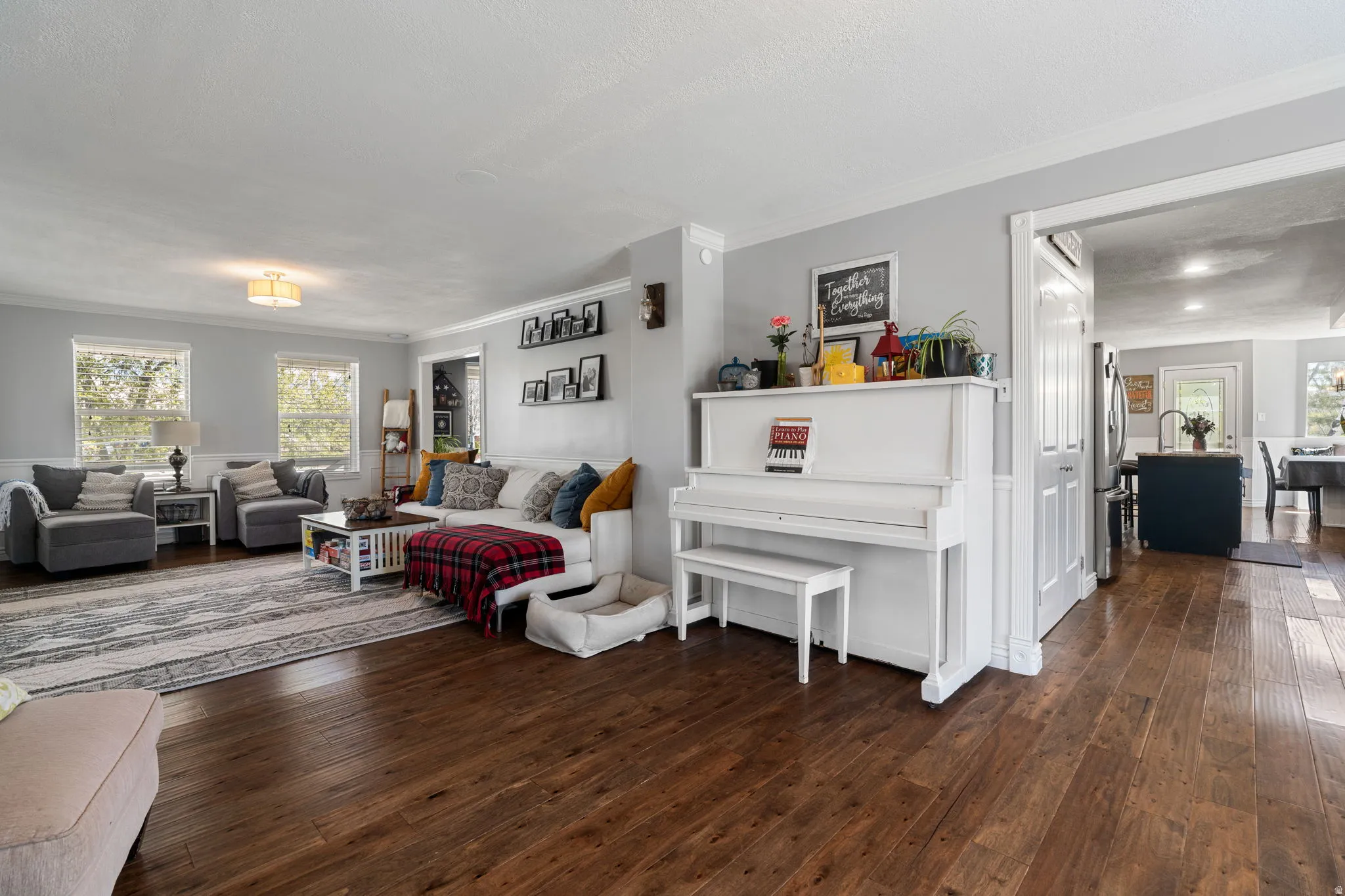 Open-concept living area featuring rich wood-finish flooring, a neutral wall palette, and crown molding