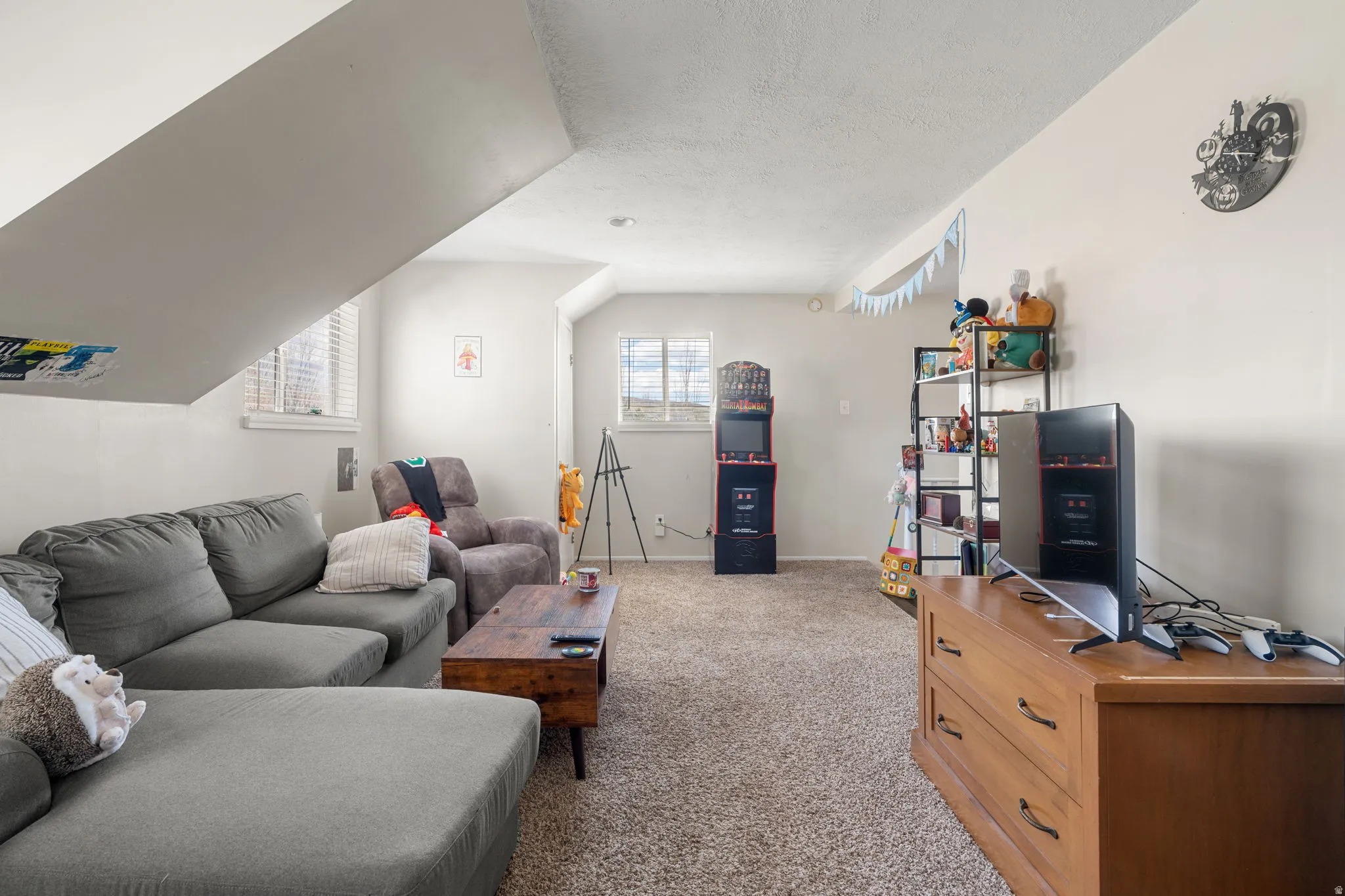Versatile bonus room featuring ample natural light from multiple windows, textured carpeting, and sloped ceiling details