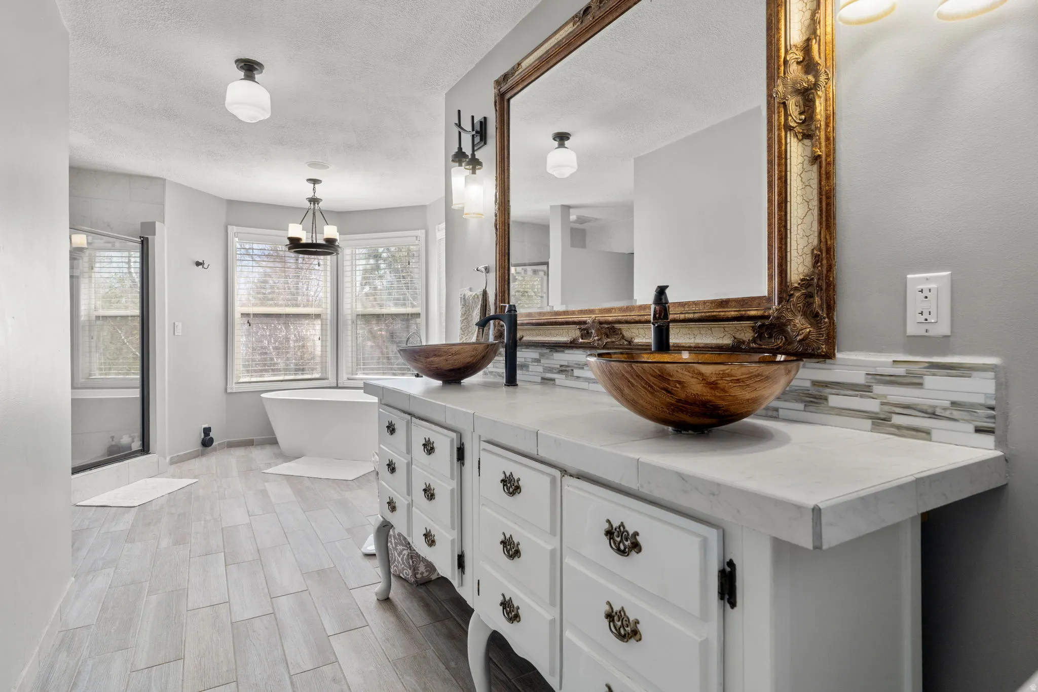 Double vanity featuring vessel sinks, a large ornate mirror, and mosaic tile backsplash