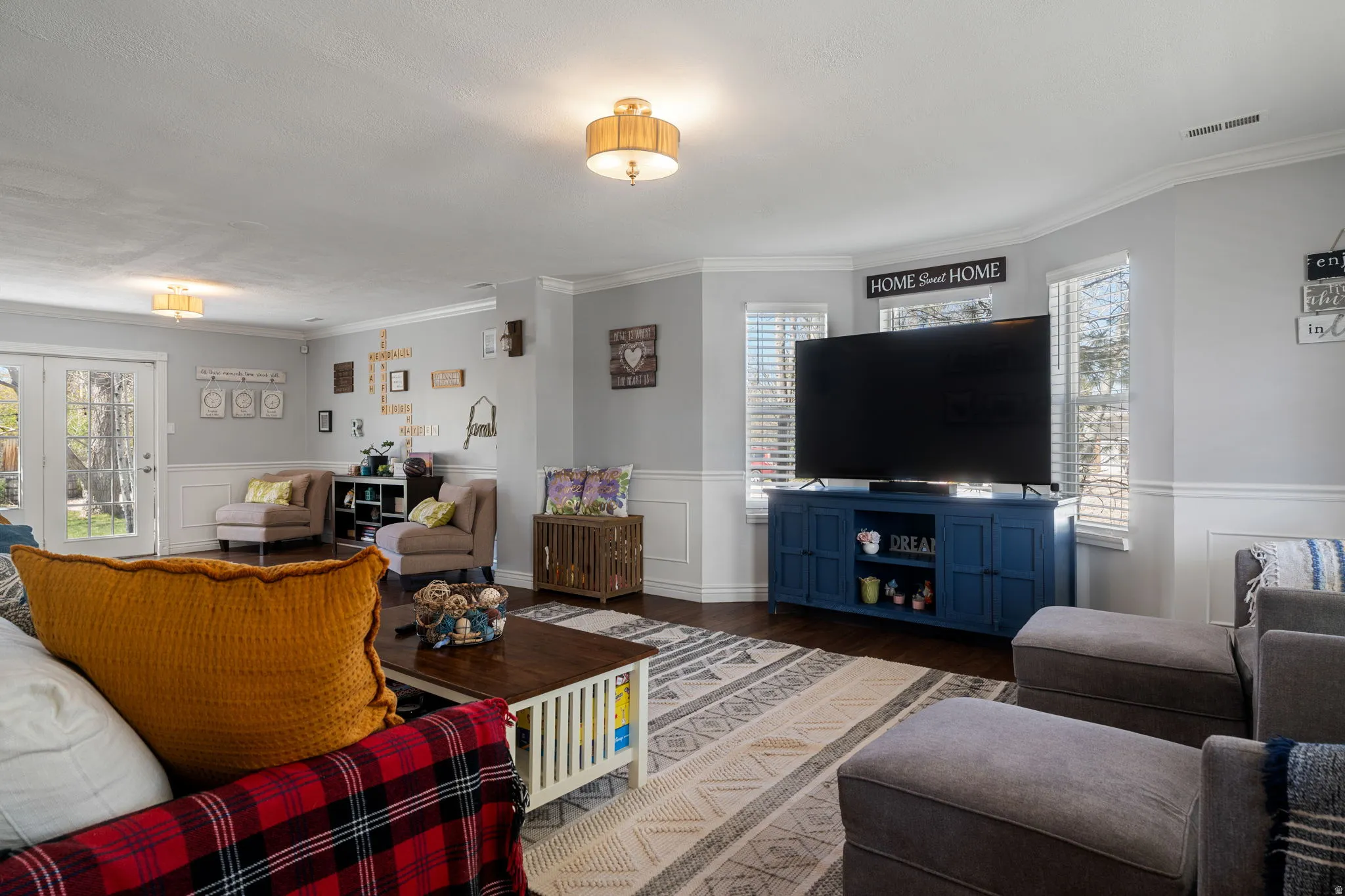 Spacious living area featuring wood-finish flooring, white wainscoting, and crown molding
