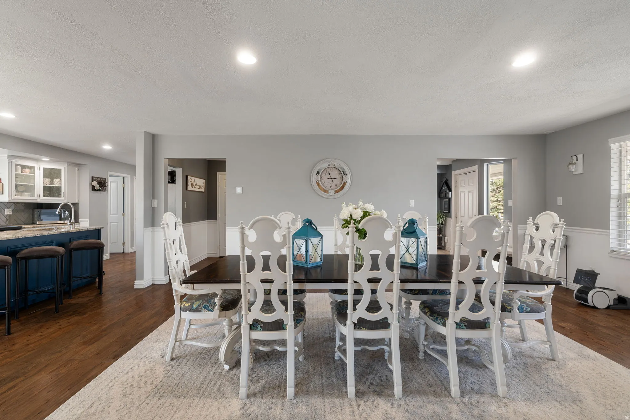 Open-concept dining area with wood-finish flooring, recessed lighting, and wainscoting