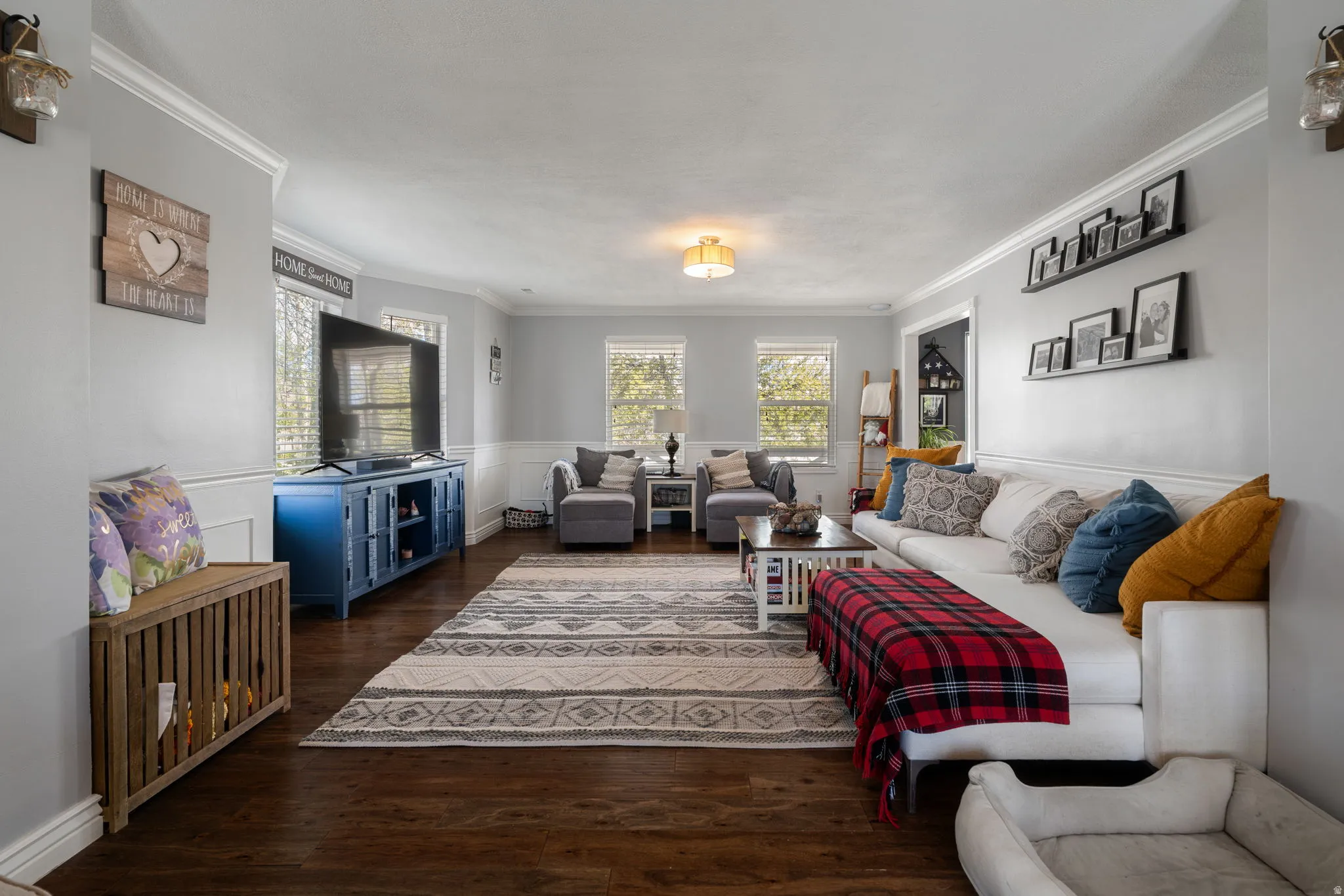 Spacious room with wood-finish flooring, white wainscoting, and crown molding