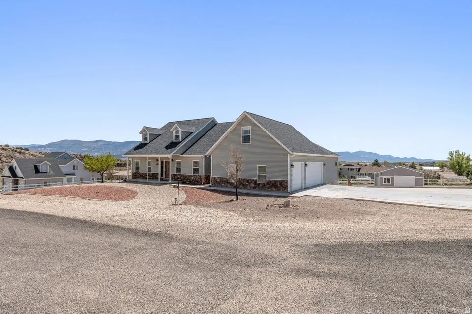 Contemporary exterior featuring light gray siding with stone accents, a covered front porch, and a two-car garage