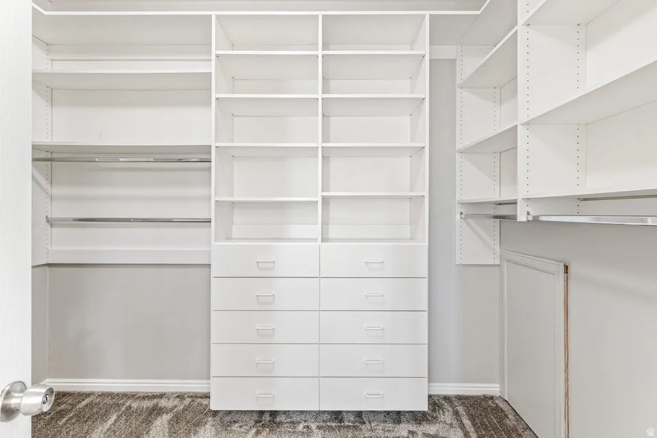 Custom walk-in closet featuring white built-in shelving, multiple hanging rods, and integrated drawer storage