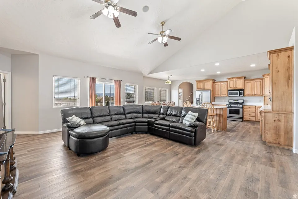 Spacious open-concept living area featuring wood-finish flooring and a vaulted ceiling