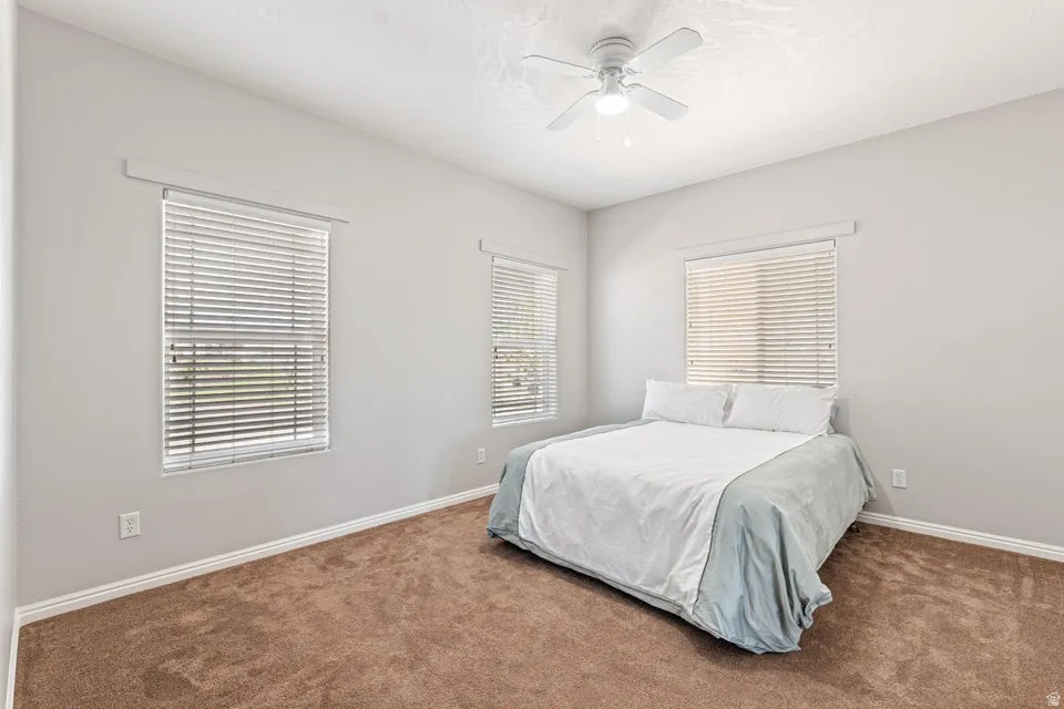 Bedroom featuring light gray walls, brown carpet flooring, and white baseboards