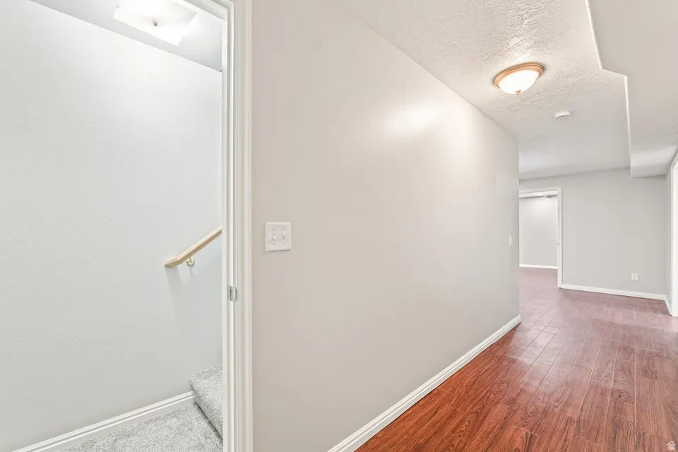 Hallway featuring wood-finish flooring, light gray walls, and white baseboards