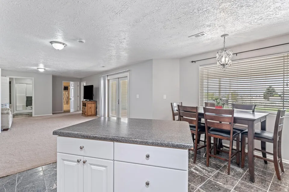Kitchen island with white cabinetry and dark stone-finish countertop