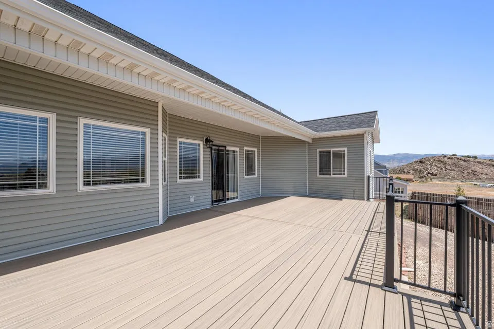 Expansive outdoor deck featuring composite decking, black metal railings, and a sliding glass door