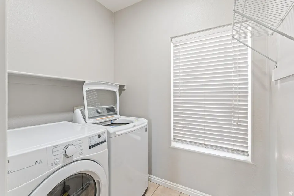 Dedicated utility area featuring a window with horizontal blinds, overhead shelving, and neutral wall tones