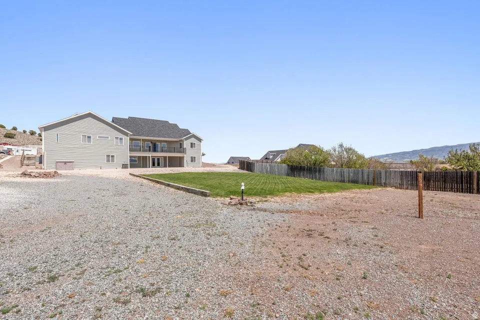 Expansive gravel yard featuring a central green lawn area
