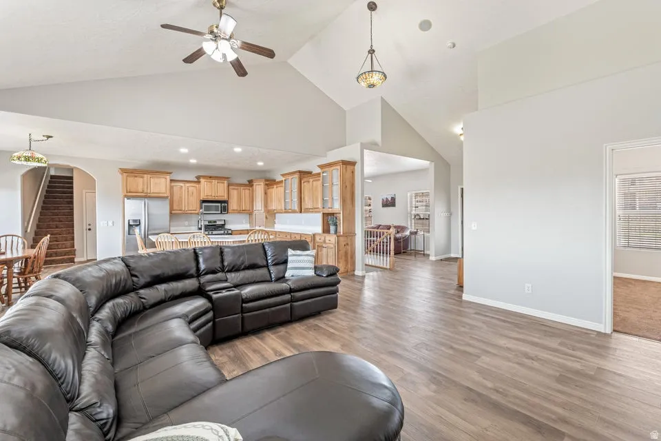 Spacious living area featuring wood-finish flooring, vaulted ceilings, and a ceiling fan
