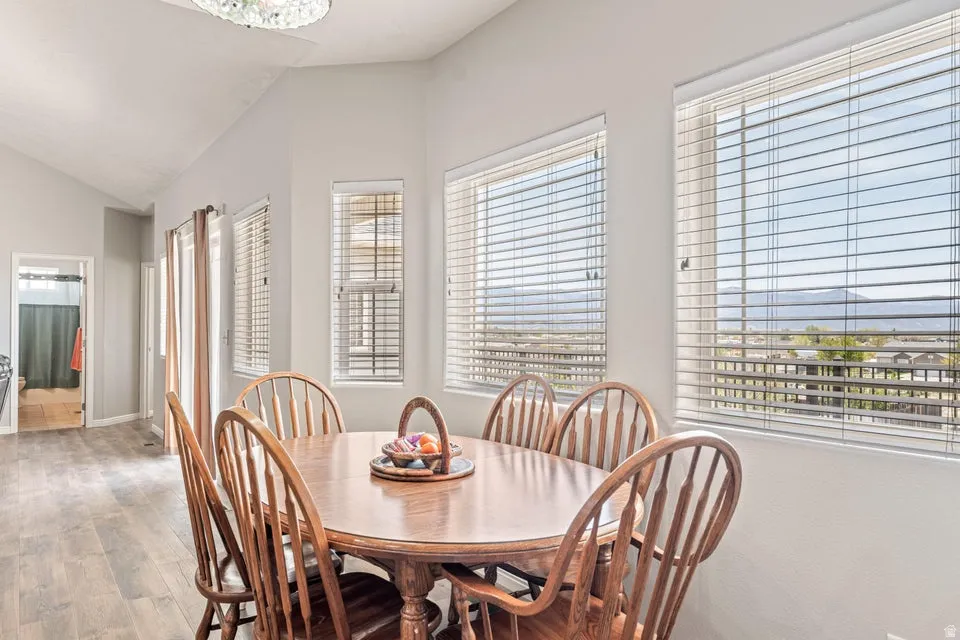 Dining area with vaulted ceilings and wood-finish flooring