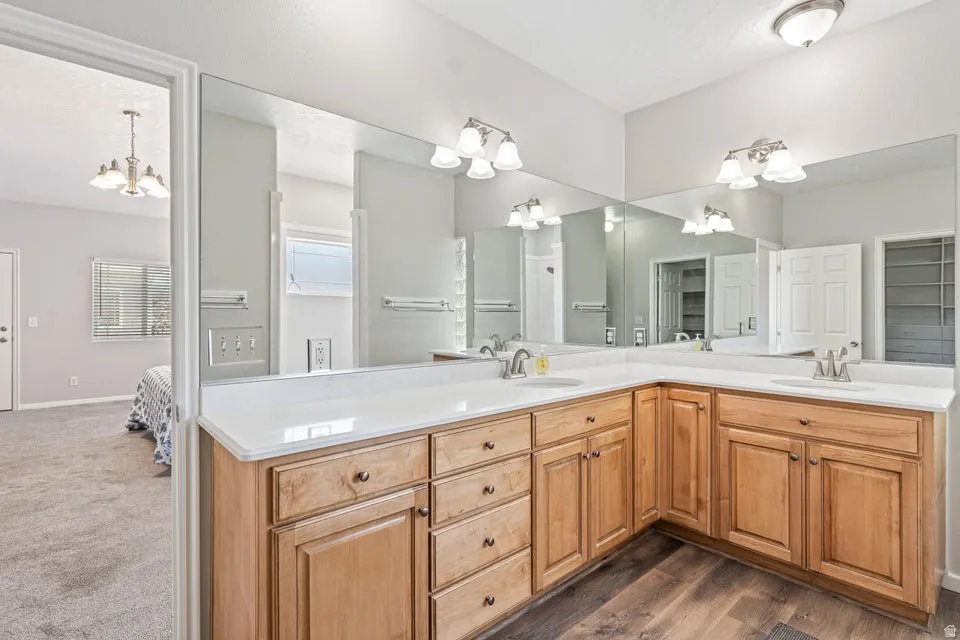 L-shaped vanity with wood-finish cabinetry, dual sinks, and white countertops
