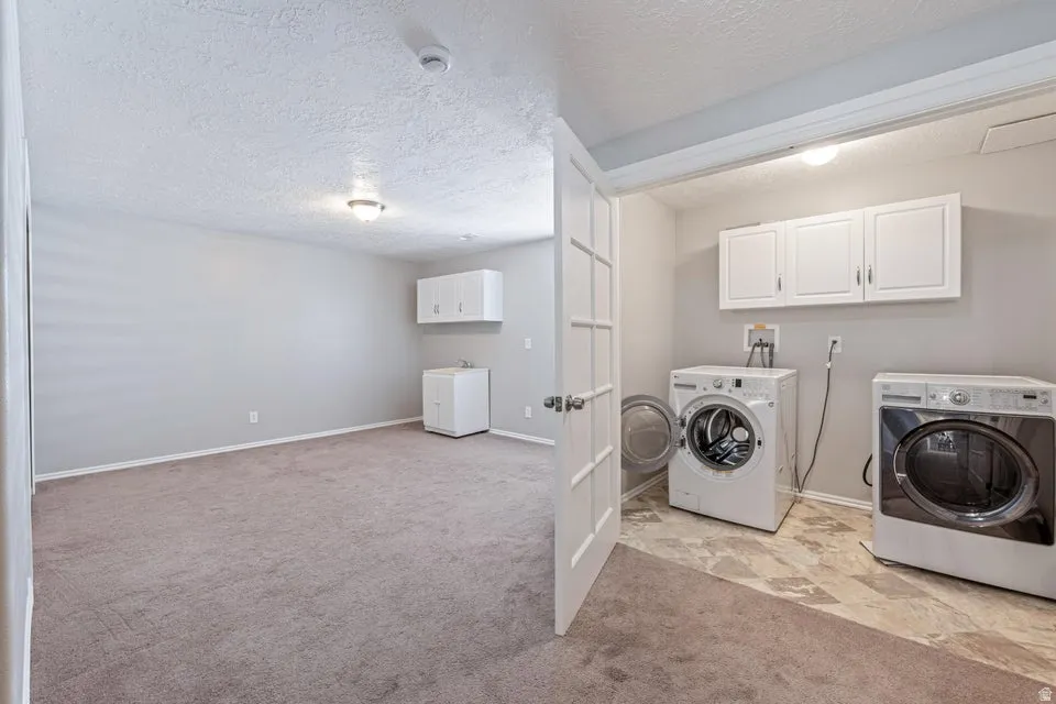 Dedicated laundry area with tile flooring and upper cabinetry