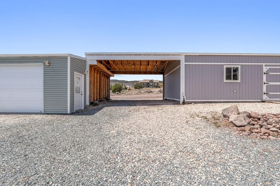 Expansive gravel driveway featuring a covered carport structure