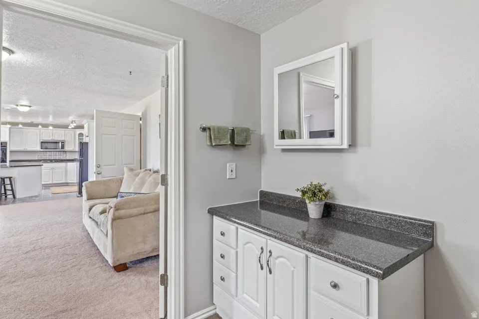 Vanity area featuring a white cabinet with dark hardware, a dark speckled countertop, and a wall-mounted medicine cabinet with a mirror