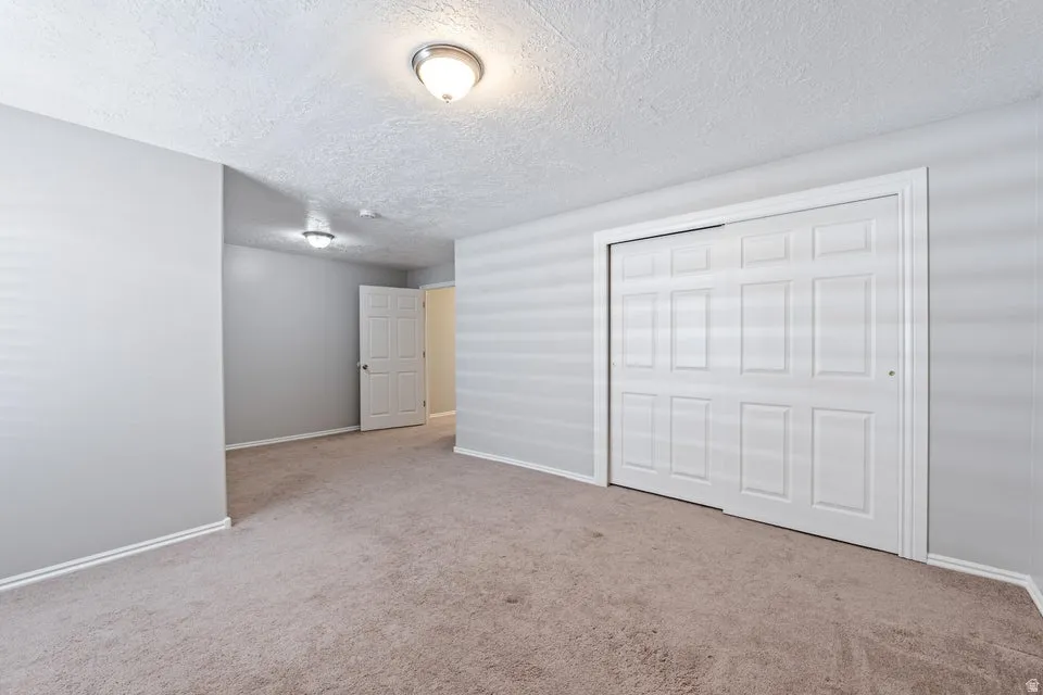 Carpeted interior space featuring light grey walls and white baseboards