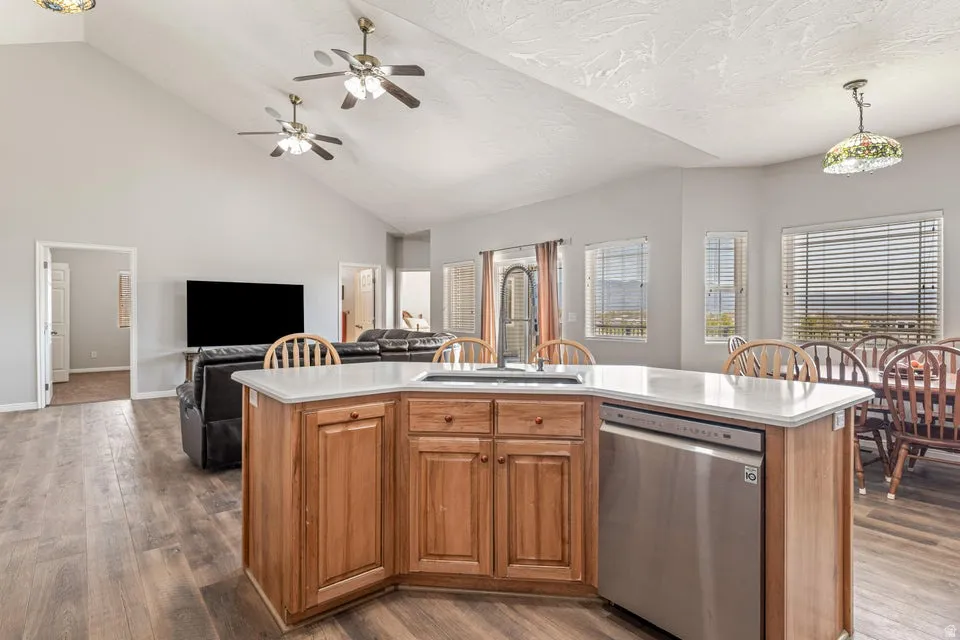 Open-concept living space featuring wood-finish flooring, vaulted ceilings, and a kitchen island with stone countertops