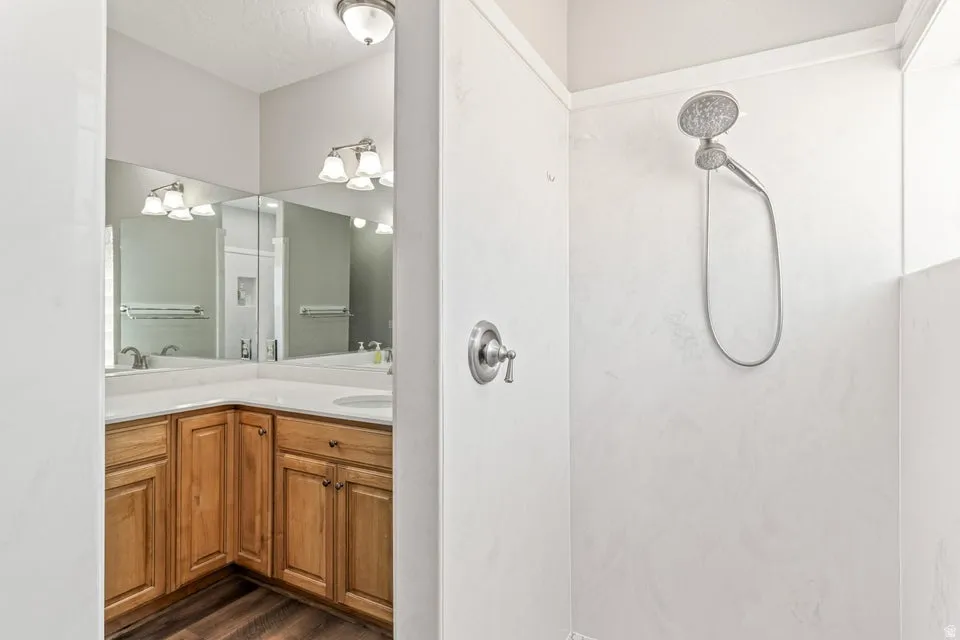 Bathroom featuring a corner vanity with wood cabinetry, light-toned countertop, and dual sinks
