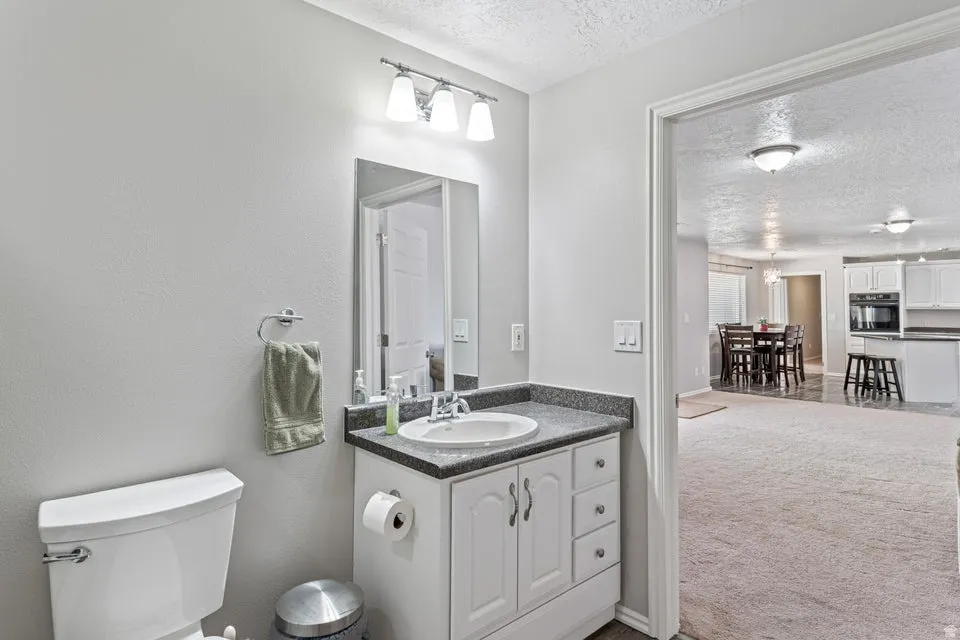 Bathroom vanity featuring a white cabinet, integrated sink, and dark countertop