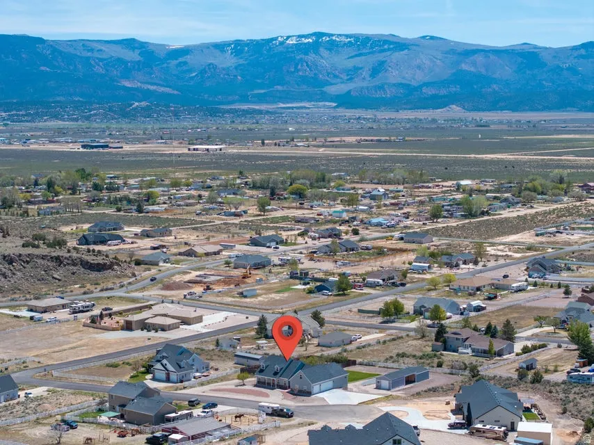 Aerial perspective showcasing a residential area with a prominent two-story home, a paved driveway, and multiple outbuildings